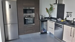 Uma cozinha moderna com eletrodomésticos de aço inoxidável, forno embutido e máquina de lavar louça.