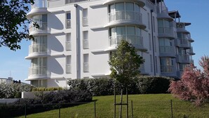 A multi-story residential building with balconies, large windows, and a well-maintained lawn.