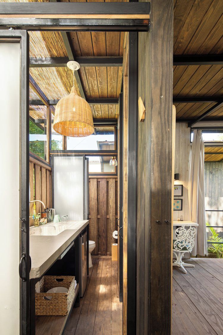 Une terrasse en bois dotée d’un espace cuisine intégré, comprenant un évier et un luminaire suspendu.