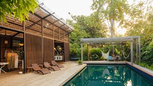A wooden deck with lounge chairs, a pool, and a covered seating area with a hammock. - Finca Victoria (Vieques)