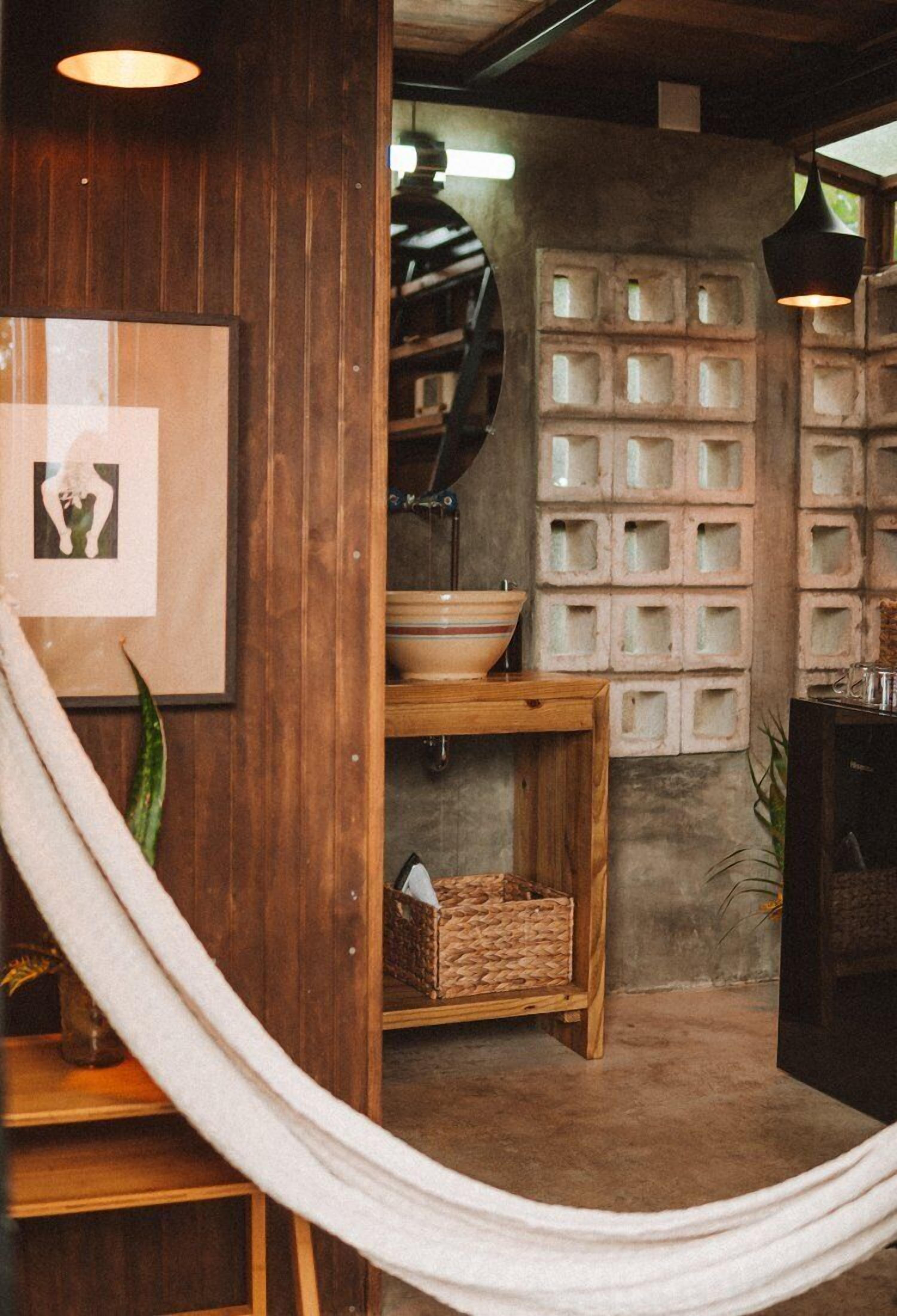 Une salle de bain rustique avec un meuble-lavabo en bois, un grand miroir et un mur en béton agrémenté de niches carrées.