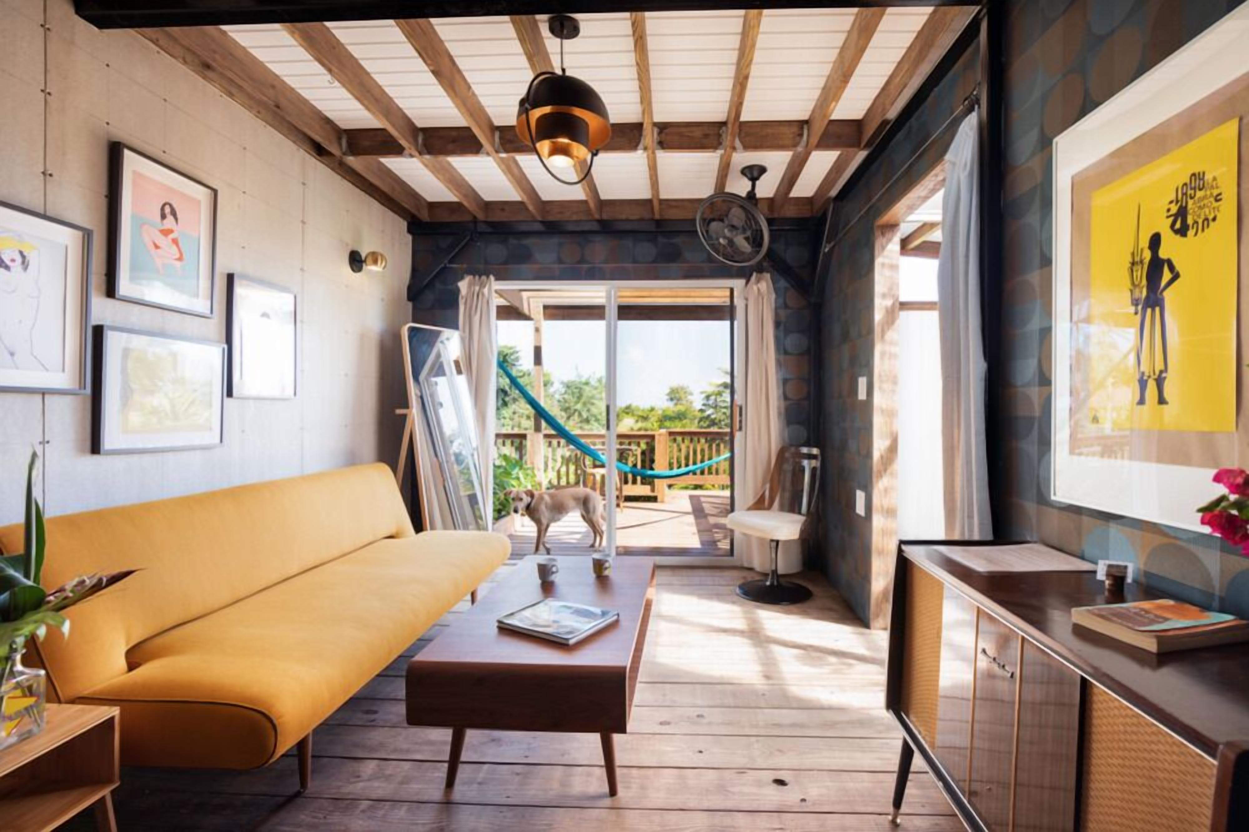 A cozy room with a wooden ceiling, a sofa, a table with a book, and a dog.