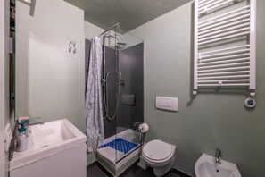 Un baño pequeño con ducha, inodoro, lavabo y bidé.