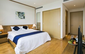 Une chambre d’hôtel comprenant un lit, des tables de chevet, une télévision, une armoire et un panier de fruits.