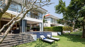 Une maison moderne dotée d’une piscine, d’un espace salon extérieur et d’une pelouse bien entretenue.