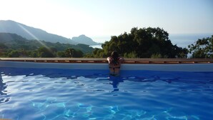 A person in a swimming pool with a view of mountains and trees. - Apartment in villa with swimming pool in Cefalù, view of the bay, App. Aranancione (Cefalu)