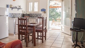 A kitchen with a dining table, chairs, a TV, and a view of the outdoors. - Apartment in villa with swimming pool in Cefalù, view of the bay, App. Aranancione (Cefalu)