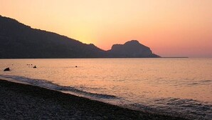A beach with pebbles and calm water, a distant mountain, and a clear sky. - Apartment in villa with swimming pool in Cefalù, view of the bay, App. Aranancione (Cefalu)