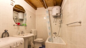A compact bathroom with a washing machine, sink, toilet, and bathtub.