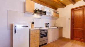 A kitchen with white cabinets, a stove, oven, and a wooden ceiling.