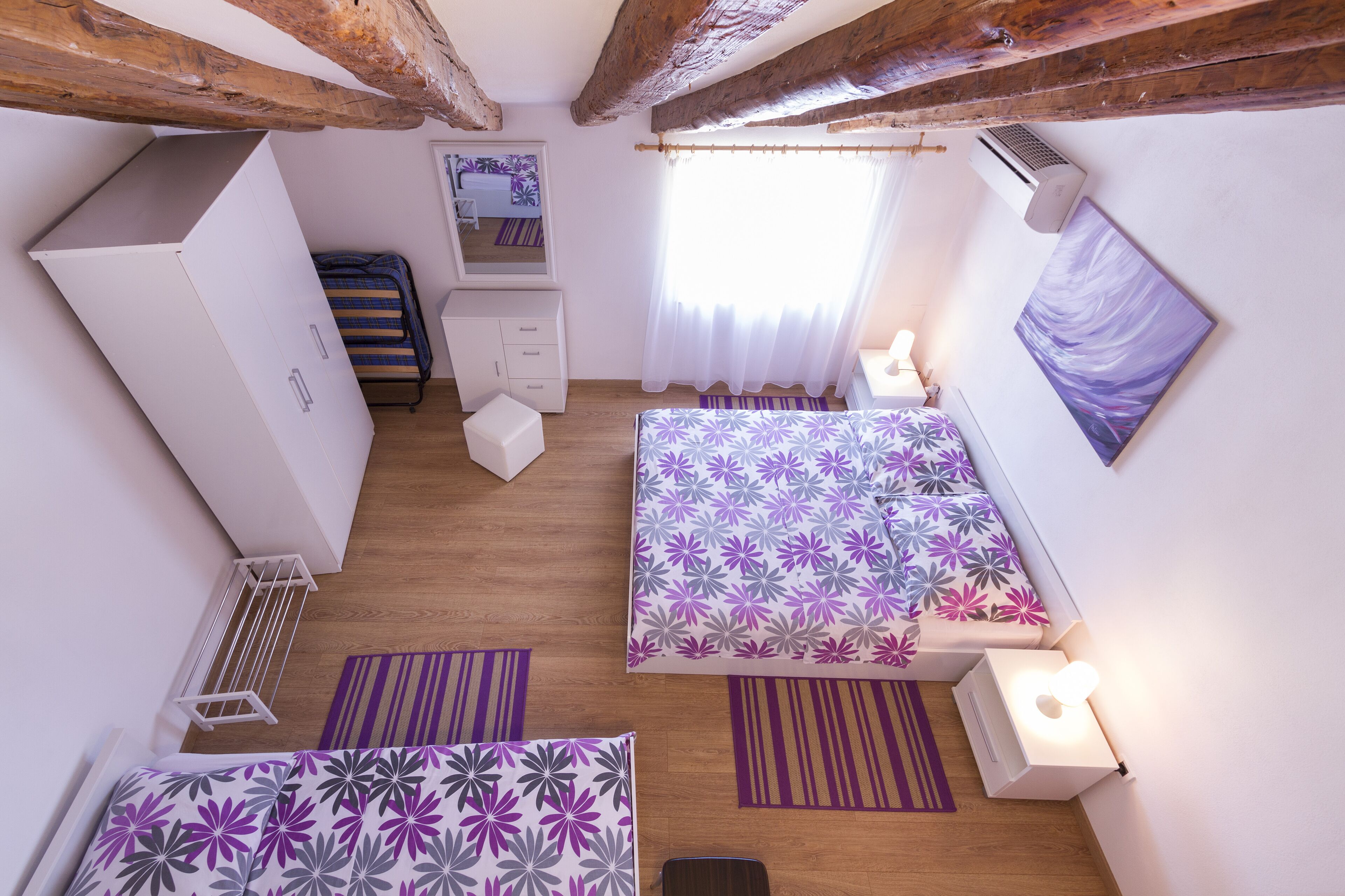 Ein Schlafzimmer mit zwei Betten, einem Schreibtisch, einem Kleiderschrank und einem Fenster mit Vorhängen.
