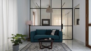Una sala de estar moderna con un sofá color turquesa, una mesa de centro redonda y un espejo grande.