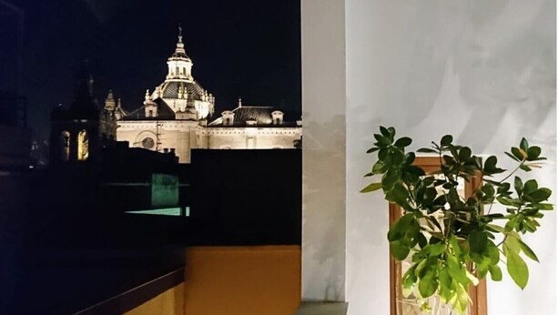 Vista nocturna de un edificio con una cúpula destacada y una zona con balcón.