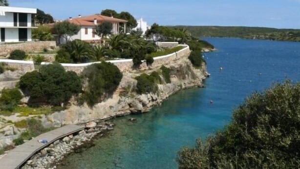 A coastal property with a stone retaining wall, a paved pathway, and a clear view of the sea. - Villa For Rent In Menorca With Private Pool, Enclosed Garden & Air Conditioni (Villacarlos)