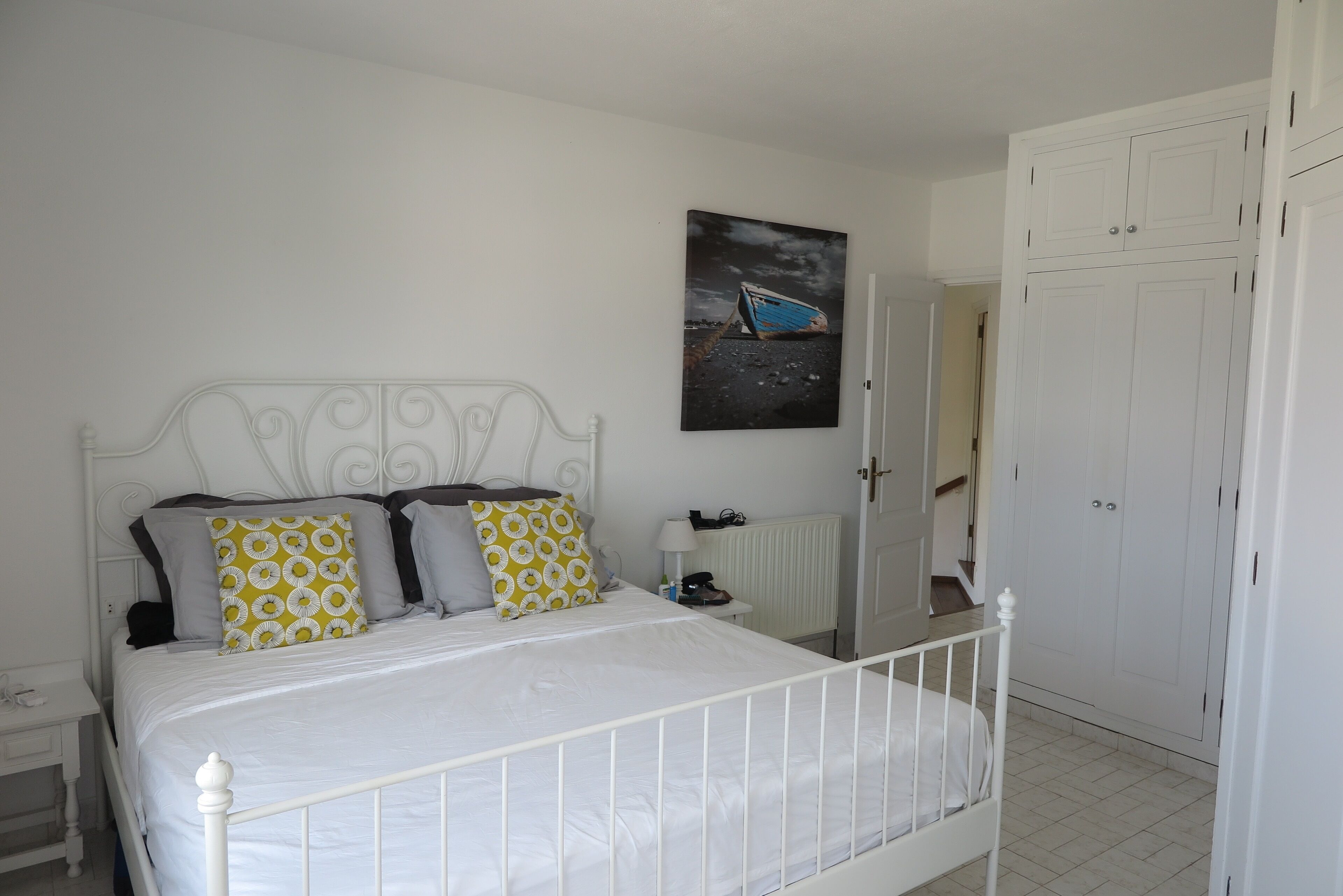 A bedroom with a white metal bed frame, a white radiator, and a white wardrobe.