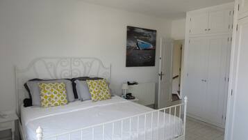 A bedroom with a white metal bed frame, a white radiator, and a white wardrobe.