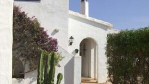 A white building with a doorway, a cactus, and a birdbath in a garden. - Villa For Rent In Menorca With Private Pool, Enclosed Garden & Air Conditioni (Villacarlos)