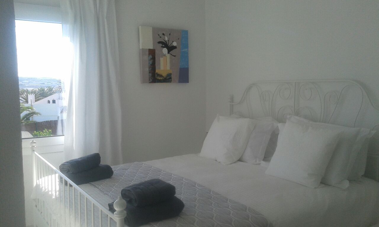 Ein Schlafzimmer mit einem Bett, Kissen, einer Decke und einem Bild an der Wand.