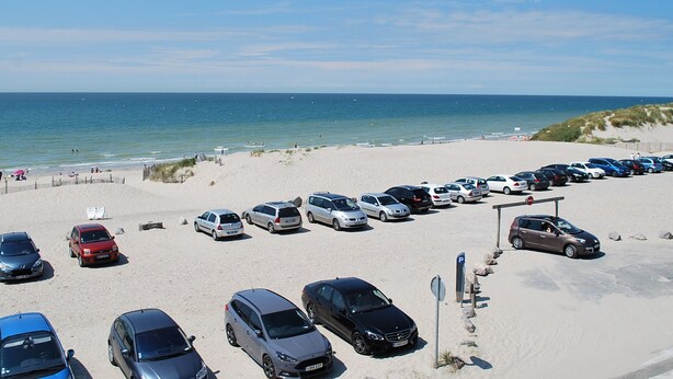 A parking lot with cars parked on a sandy beach, overlooking the ocean. - Fort-Mahon-Plage: Studio with balcony, fully equipped, private parking (Fort-Mahon-Plage)