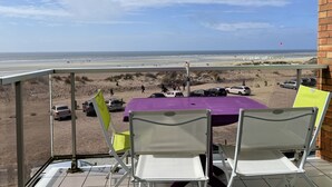 A balcony with a view of the beach, a table, and chairs. - Fort-Mahon-Plage: Studio with balcony, fully equipped, private parking (Fort-Mahon-Plage)