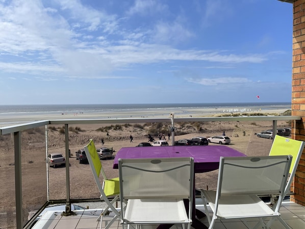 Un balcone con vista sulla spiaggia, un tavolo e sedie.