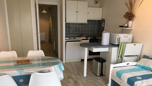 A compact room with a dining table, chairs, a bed, a kitchenette, and a small bathroom. - Fort-Mahon-Plage: Studio with balcony, fully equipped, private parking (Fort-Mahon-Plage)