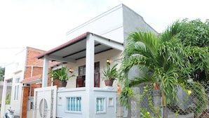 Une maison à deux étages avec un balcon, un pot de fleurs et une clôture en treillis métallique.