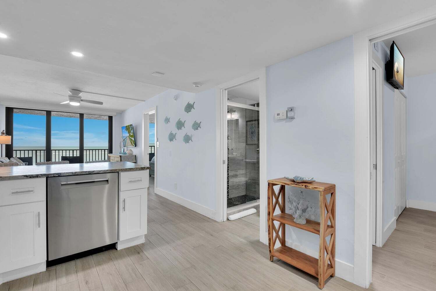 A modern kitchen with a large island, white cabinetry, and a view to the outside.