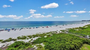 A beach with clear skies, a sandy shore, and a few tents and umbrellas. - SEA WINDS 504 - Direct Gulf Views from Coastal Renovated Beachfront Condo! (Marco Island)