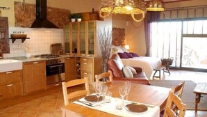 A modern kitchen with wooden cabinets, a built-in stove, and a dining area with a table set for four.