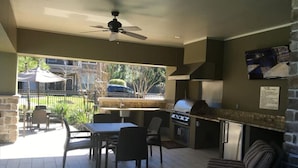 Un espace cuisine extérieur comprenant un barbecue, une table à manger et des chaises.