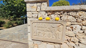 Ein Steinschild mit der Aufschrift 'Villa Lemoni' und drei Zitronen obenauf.
