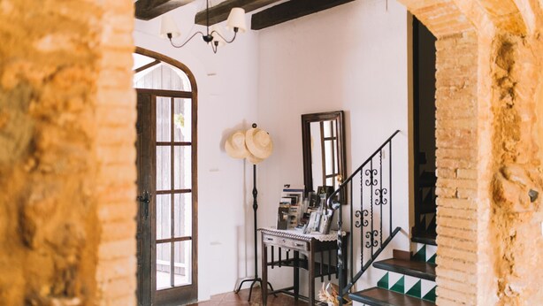 A rustic interior with exposed brick walls, a wooden staircase, and a desk with various items. - Self catering Les Orenetes for 11 people (Sant Jaume dels Domenys)