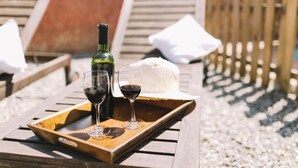 A wooden tray with a bottle of wine, two wine glasses, and a cheese wheel on a wooden table outdoors. - Self catering Les Orenetes for 11 people (Sant Jaume dels Domenys)