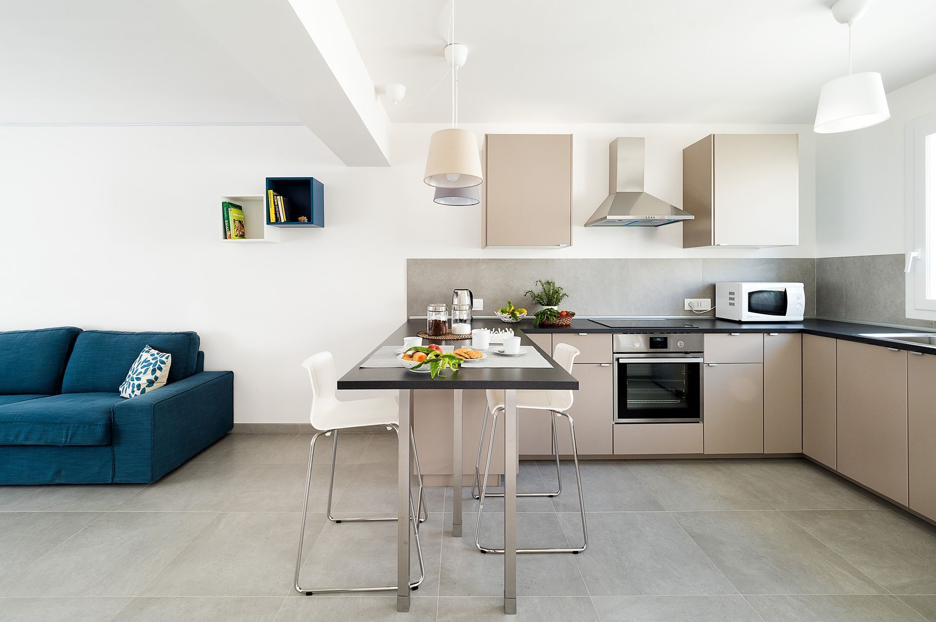 A modern kitchen with a dining area, a blue sofa, and a coffee machine.