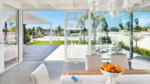 A modern hotel room with large windows, a pool view, and a dining area with a bowl of fruit. - Diantha - Villa for 10 People with Pool in Sicily, A/C, WIFI (Marsala)