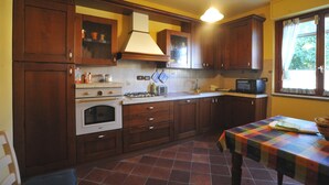 A kitchen with wooden cabinets, a stove, and a microwave. - "Il gelsomino del Perugino" home with garden, a stone's throw from the center.  (Città della Pieve)