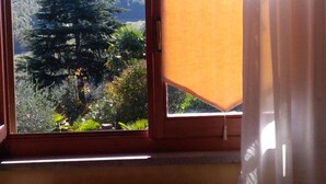 A window with a view of a forested area and a radiator below. - "Il gelsomino del Perugino" home with garden, a stone's throw from the center.  (Città della Pieve)