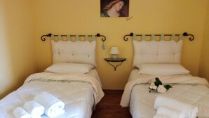 A hotel room with two beds, each with white bedding and rolled towels. There is a small table with a lamp between the beds. - "Il gelsomino del Perugino" home with garden, a stone's throw from the center.  (Città della Pieve)