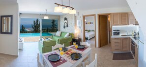 A modern apartment with a dining area, kitchen, and a view of a swimming pool. - Private stone built villa, infinity pool, BBQ, nearby Agios Nikitas (Tsoukalades)