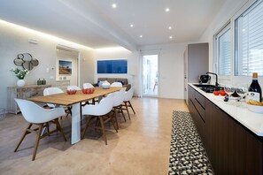 A modern kitchen with a dining area, featuring a wooden table, white chairs, and a patterned rug.