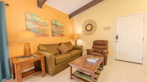 A living room with a sofa, armchair, coffee table, and two paintings on the wall. - Cranes Cove Tranquil (South Padre Island)