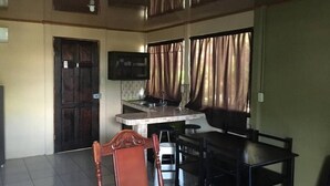 A room with a dining table, chairs, a kitchen area with a sink, and a TV mounted on the wall. - Country meets beach! Las Palmitas Costa Rica (Palmar Norte)