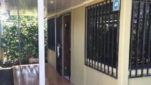 A covered outdoor area with a wooden floor, a metal railing, and a door leading to an interior space. - Country meets beach! Las Palmitas Costa Rica (Palmar Norte)