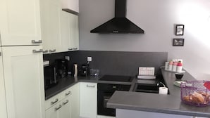 A modern kitchen with white cabinets, a black stove, and a stainless steel sink.