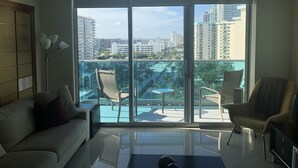 Un salon moderne doté d’une grande porte-fenêtre coulissante donnant sur un balcon avec vue sur la ville.