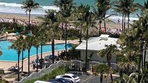 Un complexe hôtelier doté d’une piscine, de palmiers et offrant une vue sur l’océan.