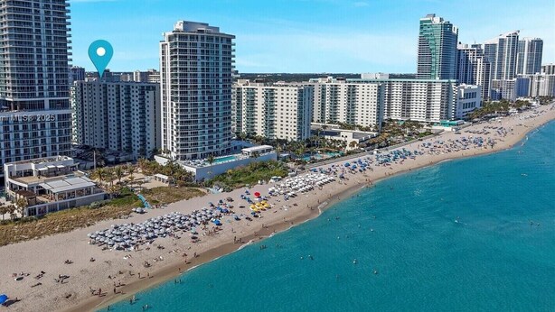 Un paysage urbain côtier avec de grands hôtels, une plage et une eau d’un bleu limpide.