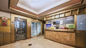 Ein Hotel-Empfangsbereich mit einer Rezeption, einem K2 Motel Schild und zwei Aufzügen.
