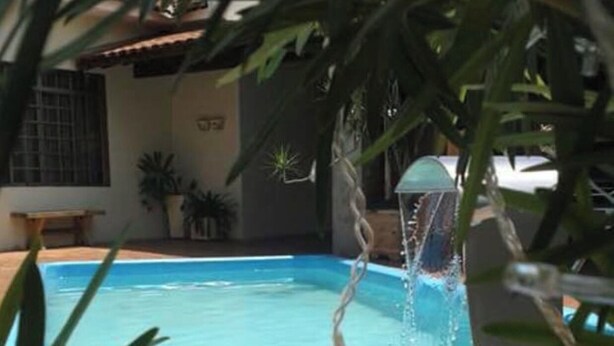 Ein Schwimmbecken mit klarem Wasser, umgeben von Kübelpflanzen und einer gefliesten Terrasse.